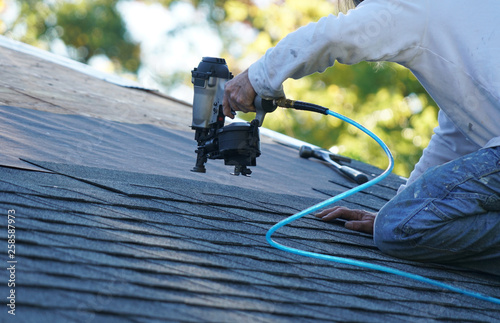 Cuadros en Lienzo handyman using nail gun to install shingle to repair roof