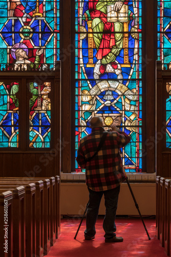 Fotomural Photographer takes photo from the aisle between pews illuminated by light from s