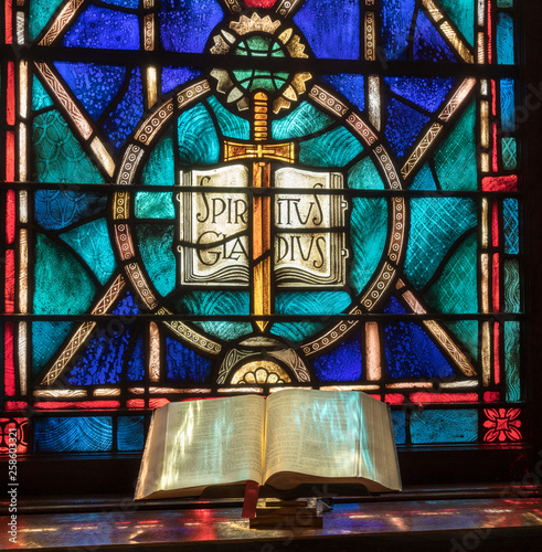 Fotografía Colored light from stained glass window in methodist church falls across open bi