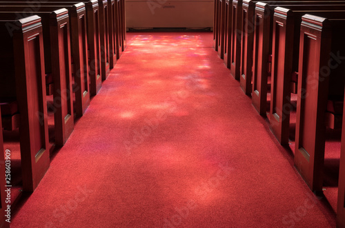 Cuadros en Lienzo Red carpeted church aisle between pews illuminated by light from stained glass w