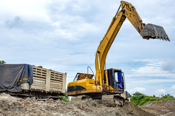 Wall Mural - Excavator loading sand onto dumper truck at a sand quarry.