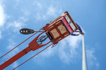 Technician on bucket truck high up of a crane to fix street light.