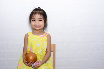 Female asian child girl sitting on a chair with white background holding a toy