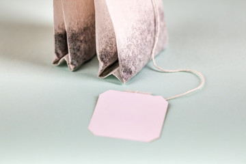 Two tea bags with white label isolated on light background