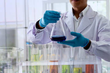 Wall Mural - blurred picture of scientist is holding the erlenmeyer flask with chemical reagent and observe the c