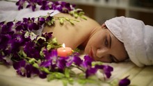 Woman On Belly In Towels Surrounded By Flowers And Candles