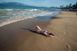 © Михаил Решетников - A young woman in a seductive bikini lying on the beach. Girl lying on the sand by the ocean