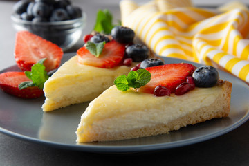 Wall Mural - Cheesecake with fresh berries and mint for dessert - healthy organic summer dessert pie cheesecake. Cheese cake. Gray background.