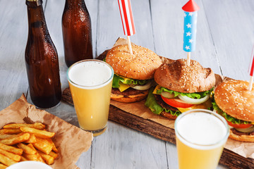 Wall Mural - three fresh and juicy burgers with American flag-style fireworks inserted into them. bbq concept picnic to celebrate independence day