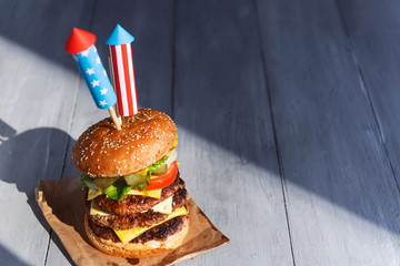 Wall Mural - a big burger with three juicy beef patties bonded with American flag firework skewers. burgar concept for the day of independence day celebration of fourth of july