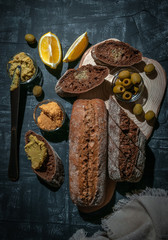 A composition of two baguettes of bran and whole grain flour. Sandwich of hummus and olives. On the wooden spacing. View from above.