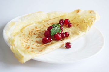 Delicious homemade pancakes with fresh berries on a white background.