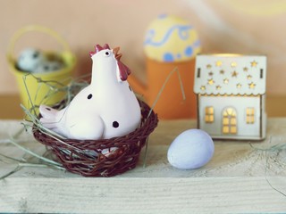 Eggs, toy chicken, toy house with illumination, Easter decor on a light wooden table