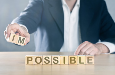 Business man puts away first two letters from the word impossible, so it becomes possible; management or solution finding concept