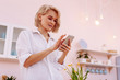© zinkevych - Appealing woman standing in kitchen and using smartphone