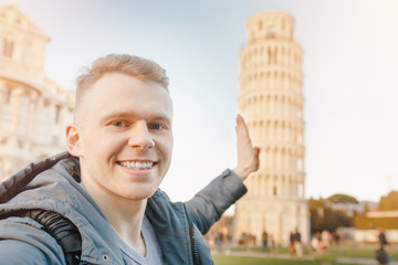 Wall Mural - Happy male traveler makes selfie photo on background Leaning Tower of Pisa