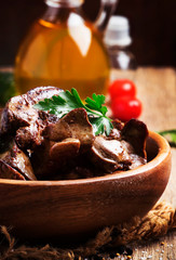 Wall Mural - Fried chicken livers in wooden bowl, vintage wood kitchen table background, vertical image, selective focus