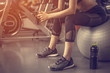 © Take Production - Fitness Girl sitting and listening to music on the ball at the fitness.
