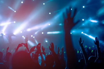 silhouettes of hand in concert.Light from the stage.