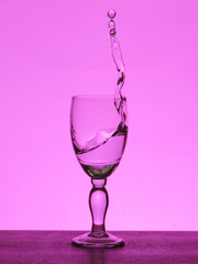 Spray liquid (clear water, red wine) from a glass goblet.