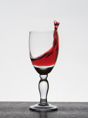 Spray liquid (clear water, red wine) from a glass goblet.