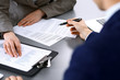 © rogerphoto - Business people and lawyer discussing contract papers sitting at the table, hands close-up. Teamwork or group operations concept