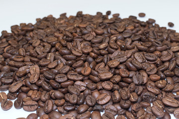 Heap of coffee beans sprinkled on a white background