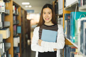 Poster - Asian student standing and reading book in the university library