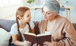 © JenkoAtaman - happy family grandmother reading to granddaughter book at home