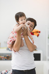 VIew of a Father and his little daughter playing together at home .