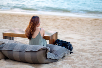 Wall Mural - A beautiful asian woman enjoy sitting on the beach by the seashore