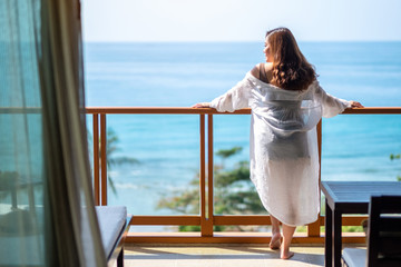 A beautiful asian woman standing and enjoy watching the sea view at balcony