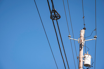 Electric poles with wires and cables set on a bright blue daylight sky.