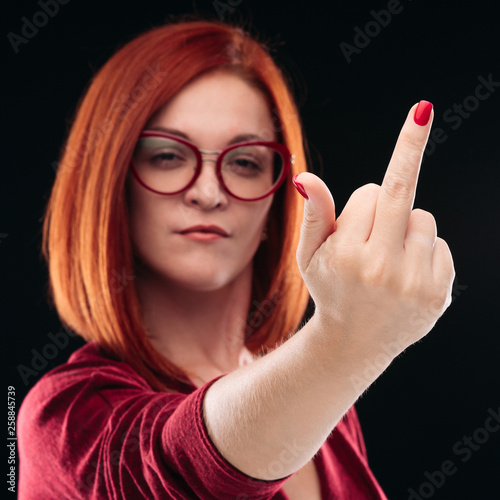 Confident And Angry Red Haired Girl With Short Hairstyle Wearing Glasses Showing Finger In Camera Emotionally Young Woman Posing Gesturing Fuck Off Out By Hand Black Studio Background Buy This Stock