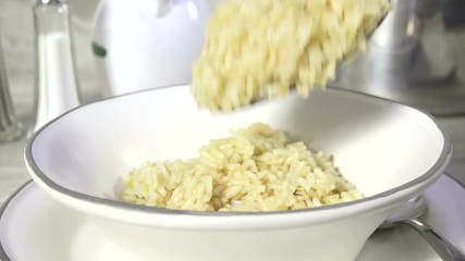 Canvas Print - Spooning hot rice into a bowl slow motion