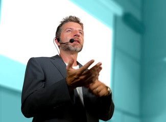 Wall Mural - confident successful man with headset speaking at corporate business coaching and training auditorium conference room talking giving motivation training from speaker stage