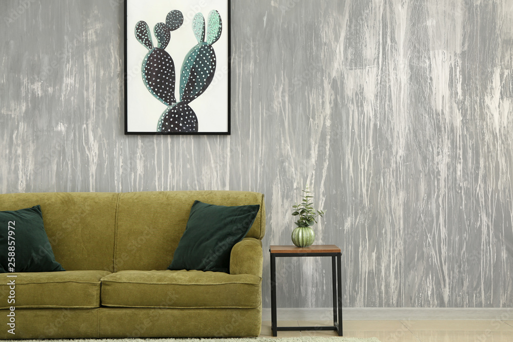 Soft sofa and table near grey wall in room