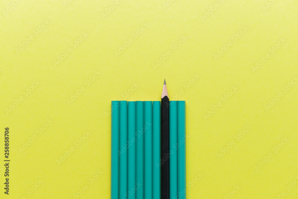 One black whittled pencil among blunt ones on color background. Concept of uniqueness