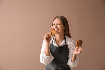 Wall Mural - Happy female baker with tasty cookies on color background