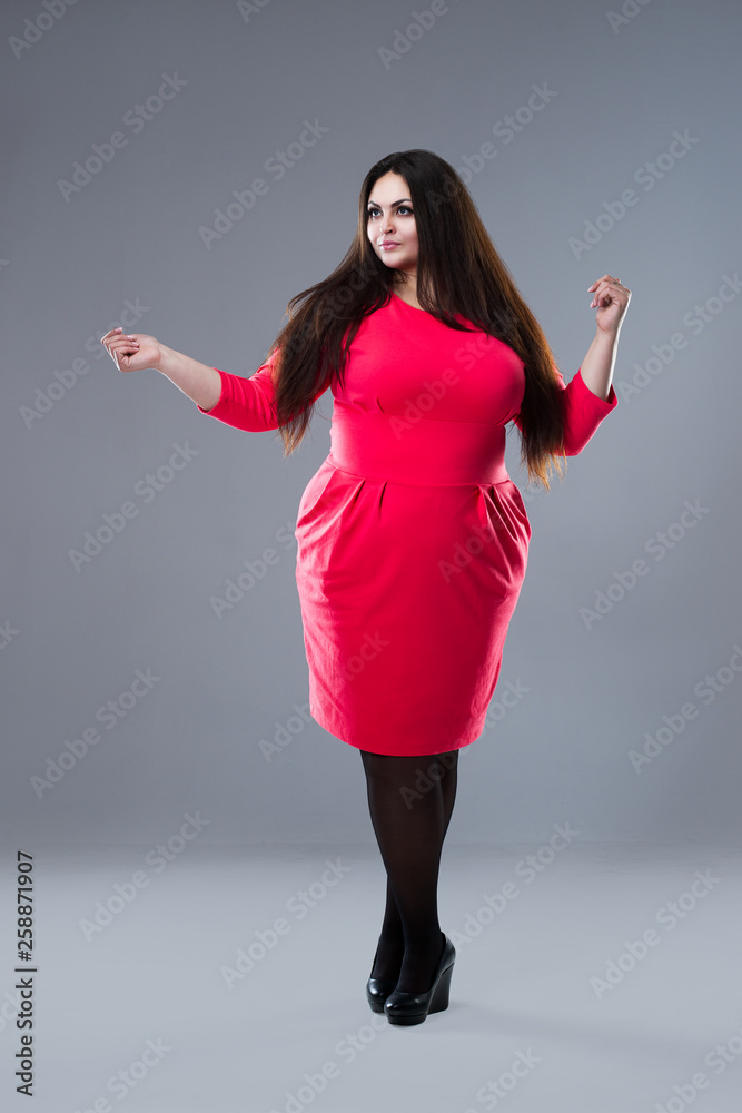 Brunette plus size fashion model in red dress, fat woman with long hair on  gray background, body positive concept Stock Photo | Adobe Stock