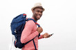 © mimagephotos - handsome african american man with hat and bag holding smartphone against white background