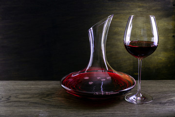 glass of red wine and bottle on wood background