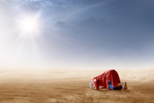 Rear View Of Asian Muslim Man Praying In Prostration Position On Desert