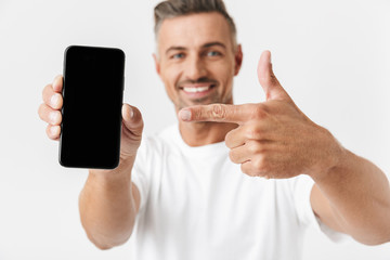 Wall Mural - Image of successful man 30s wearing casual t-shirt holding and demonstrating cell phone