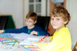 © Irina Schmidt - Two little kids boys at home making homework. Little concentrated children writing with colorful pencils, indoors. Elementary school and education. Siblings and best friends learning.