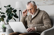 senior man in glasses looking at laptop at home