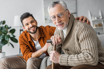 Wall Mural - selective focus of cheerful senior man and handsome son looking at camera