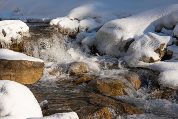 Water flowing in rapids over stone, in the winter mountains