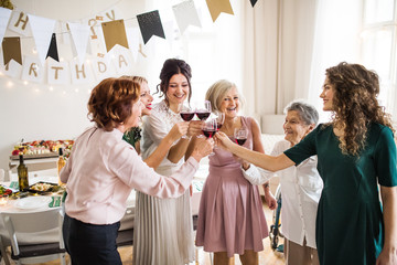 Wall Mural - A multigeneration family clinking glasses on a indoor family birthday party.