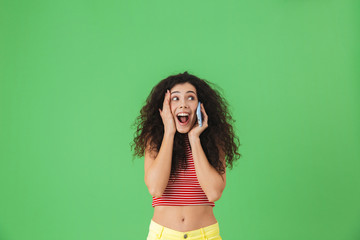 Poster - Photo of cheerful woman smiling and talking on cell phone isolated over green background